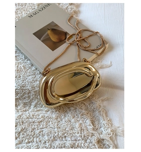 Macro view of golden evening clutch with ring handle and bead chain strap detail