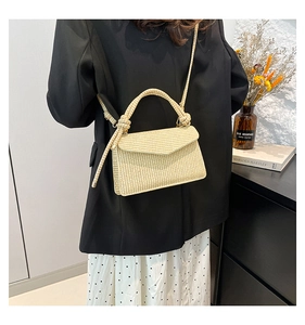 Detail of beige woven crossbody bag with decorative knotted handle and sleek flap closure