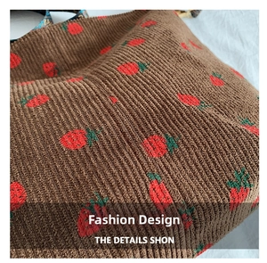 Detail of brown corduroy bucket bag with red strawberry embroidery and ribbed texture