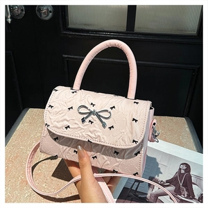 Détail du sac à main plissé rose avec imprimés nœuds noirs et boucle argentée