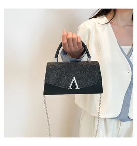 Close-up of glittery black mini handbag with silver V-clasp and metallic chain strap