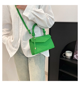 Detailed texture of green woven crossbody bag with metal buckle and top handle