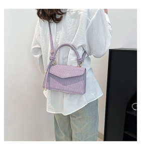 Detail of lavender woven handbag with magnetic flap and gold hardware on model