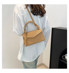 Detailed back view of a light brown woven crossbody bag on model with braided shoulder strap