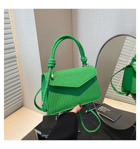 Detail of bright green woven rope crossbody bag showing texture and mirror reflection