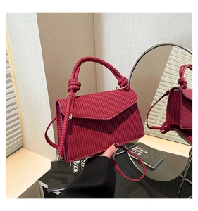 Close-up of woven texture and knot handle detail on a burgundy rectangular handbag