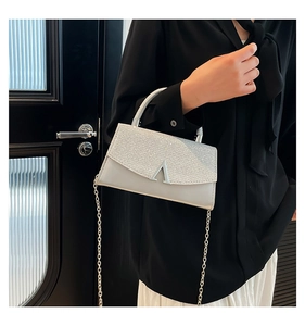 Close-up of stylish silver sequin handbag with V-shaped metal buckle and chain strap