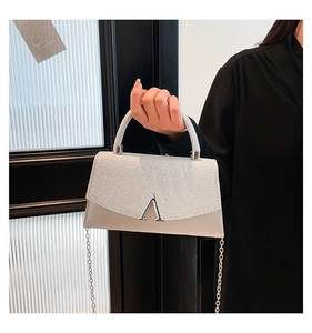 Detail of a mini crossbody bag with a rhinestone flap and silver V metal logo