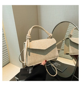 Detail of woven straw crossbody bag with striped texture and envelope flap closure