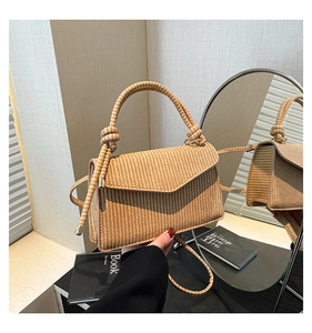 Detail of hand-woven striped handbag featuring a unique triangle flap and metal closure