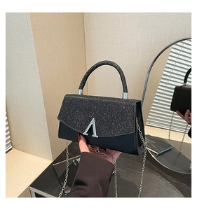 Detail of black glitter flap handbag with silver V-shaped metal and chain strap