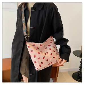 Corduroy pink shoulder bag with strawberry embroidery and woven ethnic strap detail