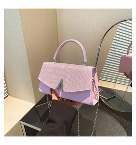 Detail showing pink rhinestone handle and silver V logo buckle on woman shoulder bag
