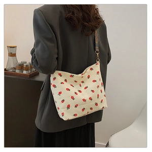 Close-up of strawberry corduroy bag with vintage woven strap and golden metal buckle