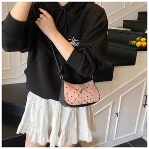 Detail of pink heart-quilted crossbody bag with silver bow and black leather contrast
