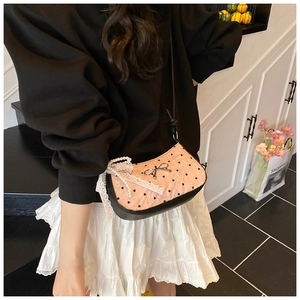 Detail of pink polka dot handbag with metal bow, lace ribbon and pearl charm