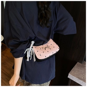 Close-up of pink quilted crossbody bag with black bows, lace ribbons and pearl tassels