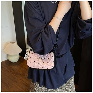 Close-up of pink satin bag featuring black bow patterns and metallic bow buckle detail