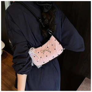 Detail of light pink wrinkled shoulder bag with black bows, lace trim and pearl strap