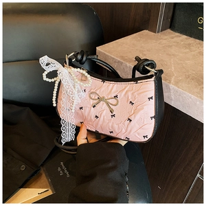 Detail of pink bow handbag featuring silver bow charm, pearls and lace ribbon accents