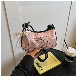 Detail of pink pleated handbag featuring black hearts, metal bow, and pearl lace charm