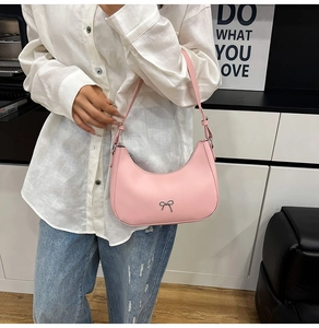 Detail view of pink hobo shoulder bag with a silver metal bow accent and adjustable strap