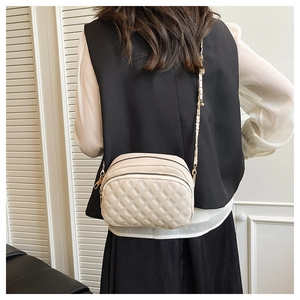 Detail of beige quilted mini crossbody bag with multi-layer zipper and chain strap