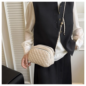 Detail of off-white quilted crossbody bag with pearl chain strap and double zipper layers