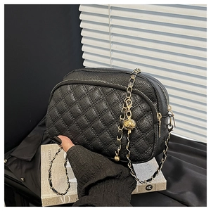 Détail du sac bandoulière en cuir matelassé noir avec chaîne dorée et boucle ajustable