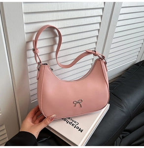 Detail of pink crescent bag showing silver bow ornament and smooth leather texture