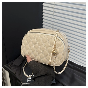 Détail du sac bandoulière crème matelassé avec double zip et chaîne dorée à boule