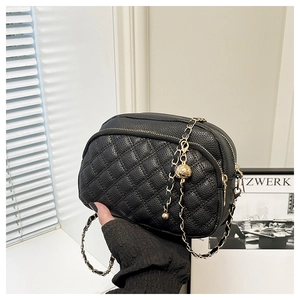 Detail of black quilted leather bag with gold chain strap and metal ball adjuster
