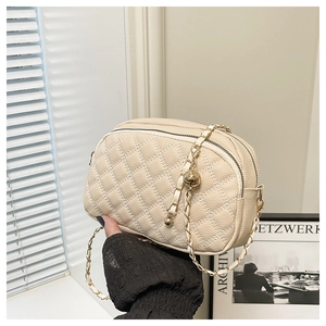 Detail of beige quilted camera bag with gold chain strap and spherical adjustment bead