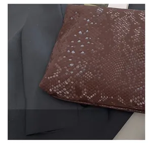 Close-up of brown snake pattern leather texture with precise stitching detail on handbag