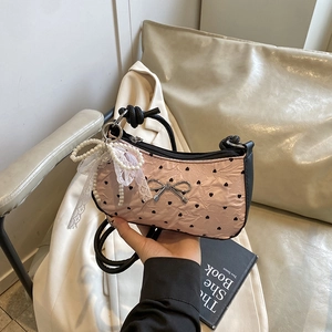Pink heart-print shoulder bag with metal bow and lace pearl charm on neutral background