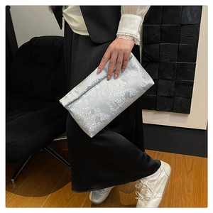 Detailed view of silver snake-pattern envelope clutch bag with fine embossed texture