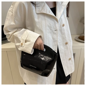Detail of minimalist black patent leather handbag with Fashion & Bags logo engraving