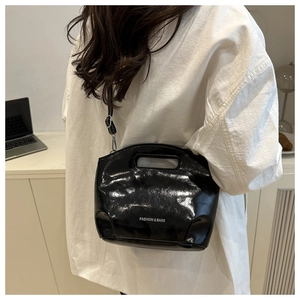 Close-up of black patent leather handbag with FASHION & BAGS logo and silver hardware