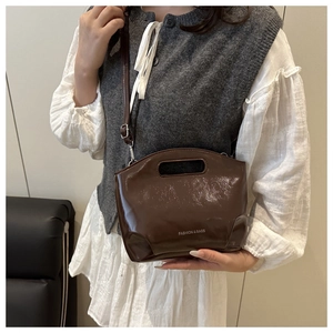 Detail of dark brown patent leather bag showing texture and adjustable shoulder strap