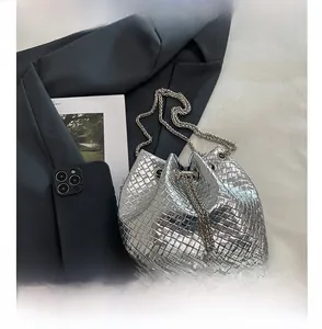 Close-up of silver woven bucket bag next to a phone showing compact portable size