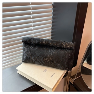 Detail view of black snakeskin texture envelope clutch on a minimalist background