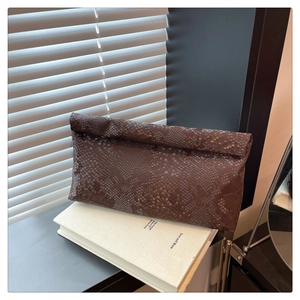 Detailed view of dark brown snakeskin patterned envelope clutch bag in natural window light