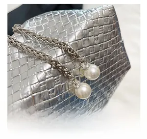 Close-up of silver woven handbag texture with delicate chain and white pearl charms