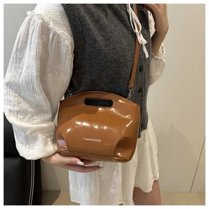 Detail of glossy brown leather tote showing hollowed handles and logo print