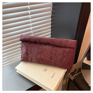 Detail of wine red snake-skin embossed texture on a sleek rectangular clutch bag