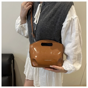 Close-up of caramel brown patent leather tote with oval handle and shoulder strap