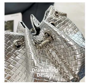 Detailed macro of silver woven bucket bag featuring metal eyelets and chain drawstring