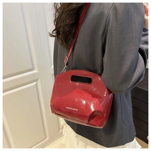 Detail of burgundy glossy leather bucket bag showing cutout handle and fashion text logo