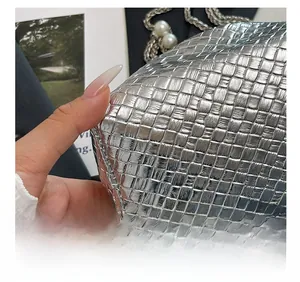 Detail of silver woven bucket bag featuring premium pearl handle and metallic texture