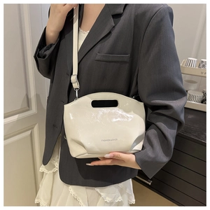 Detail of cream patent leather bucket bag featuring Fashion & Bags logo and slim strap